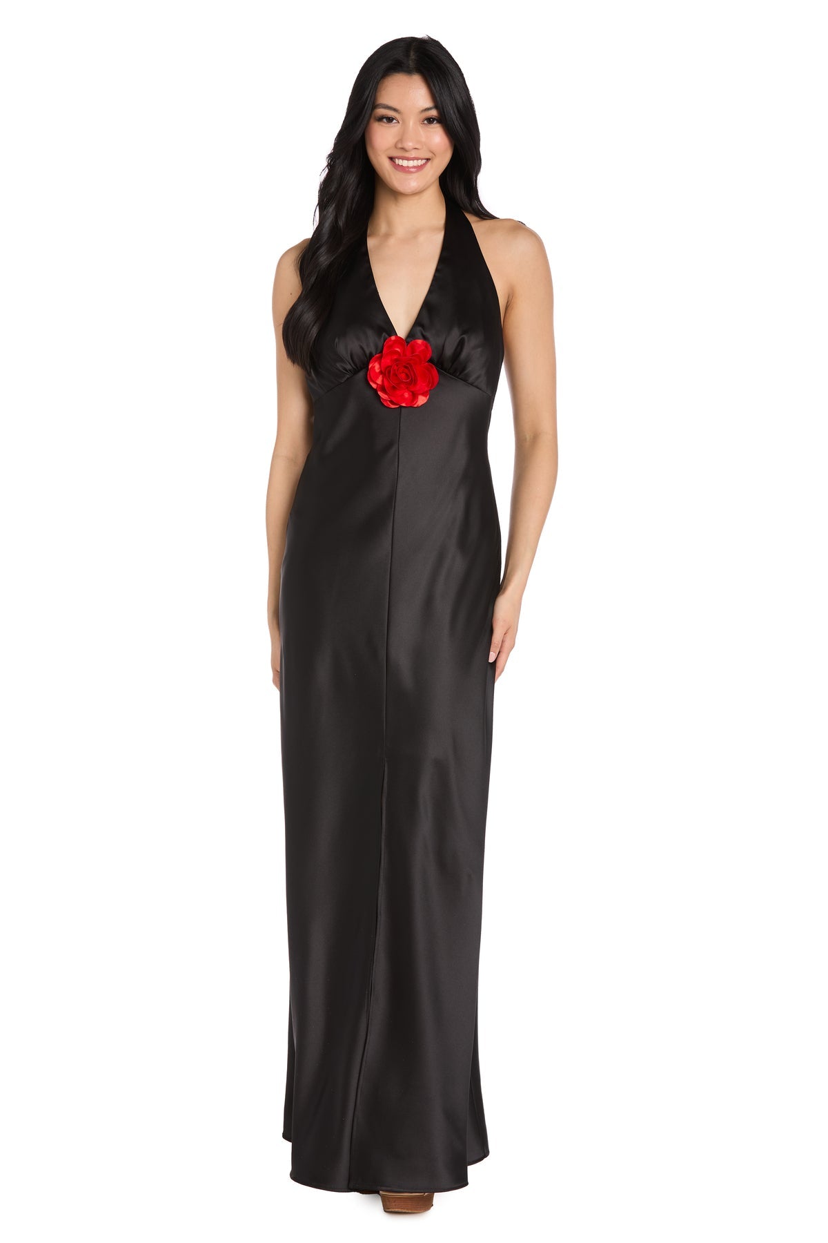A woman in the R&M Richards 3773, a long black satin halter formal dress with a floor-length silhouette and large red flower detail at the center front—an elegant choice for any black-tie event.